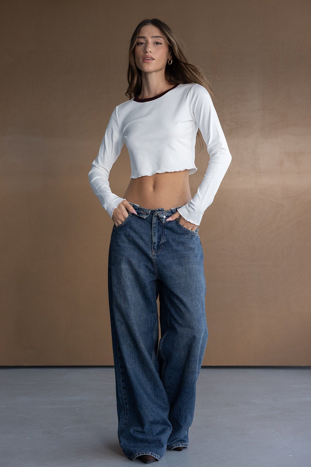 אישה לובשת טופ לבן ארוך בטן וג'ינס רחב, אופנת רחוב לנשים צעירות