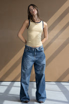 דוגמנית לובשת גופייה צהובה עם שוליים כהים ומכנסי ג'ינס רחבים, אופנת נשים קז'ואל