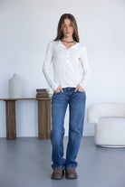 אישה לובשת חולצת כפתורים לבנה וג׳ינס בגזרה ישרה, אופנת נשים עדכנית