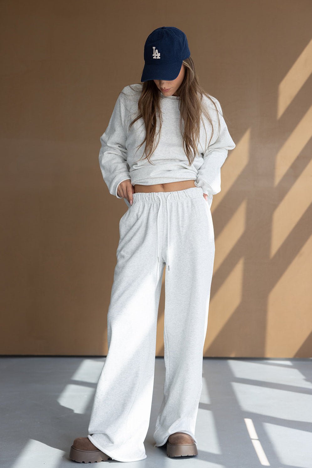 אופנת נשים סט טרנינג אפור, מכנסיים וחולצה ארוכה, כובע כחול, נעלי פלטפורמה חומות