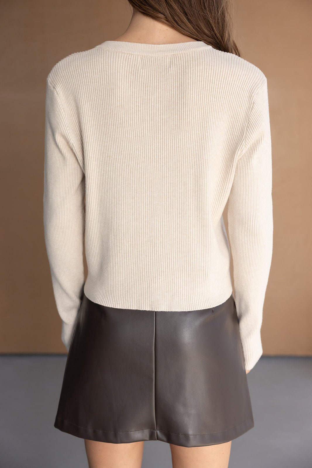 חצאית מיני דמוי עור בצבע שחור עם סוודר קרם לנשים, צילום מאחור, אופנה עדכנית
