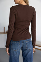 חולצת נשים חומה ארוכת שרוולים ומכנסי ג'ינס בגזרה רחבה, צילום מאחור