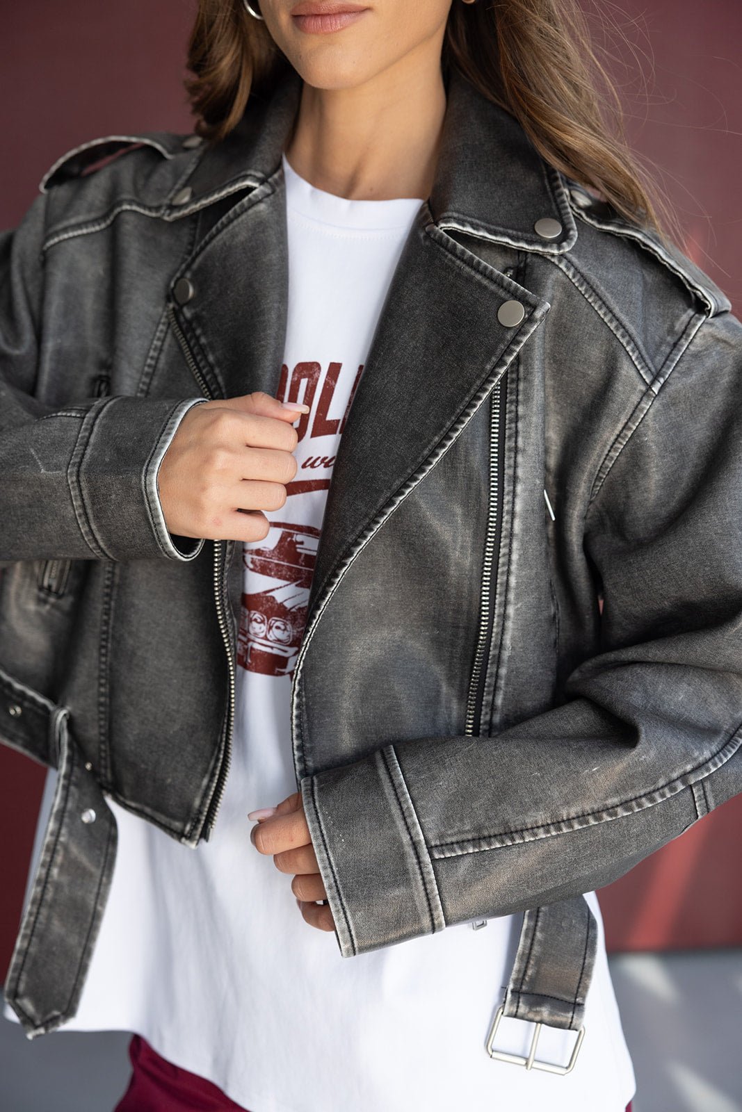 נשים לובשת ז'קט אופנתי בג'ינס דמוי עור בצבע אפור כהה עם חולצת טי לבנה הדפס אדום