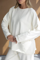 דוגמנית עם סט בגדי נשים טרנדי בצבע שמנת, סווטשירט ארוך ומכנסיים תואמים