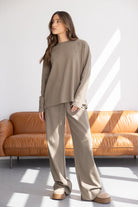 דוגמנית לובשת סט טרנינג נשים בז׳ אופנתי, חולצה ומכנסיים רחבים, בסלון מואר