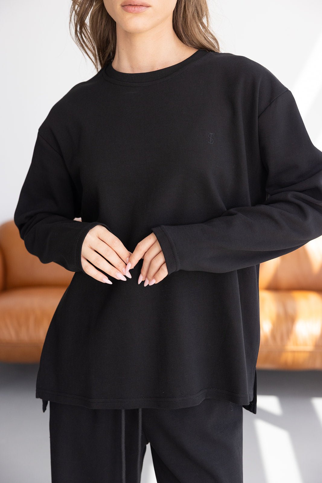 דוגמנית לובשת חולצת טרנינג שחורה לנשים עם שרוולים ארוכים בסגנון קז'ואל