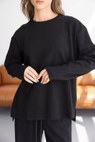 דוגמנית לובשת חולצת טרנינג שחורה לנשים עם שרוולים ארוכים בסגנון קז'ואל