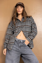 דוגמנית לובשת חולצה משובצת אפורה ומכנסי ג'ינס רחבים, כובע קז'ואל חום