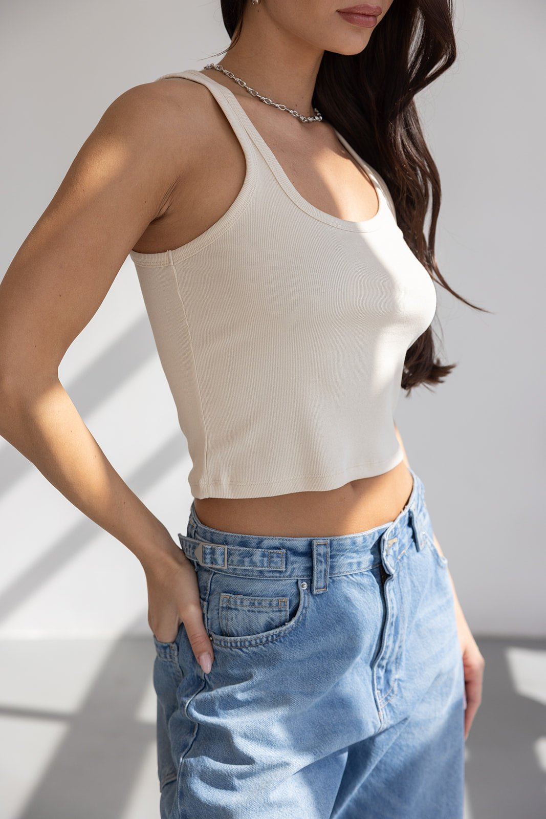 דוגמנית עם גופיית ריב צבע בז' ומכנסי ג'ינס ברוח רחבה, אופנת קיץ לנשים