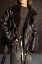 אישה לובשת מעיל עור חום עם פרווה וביגוד חורף אופנתי לנשים