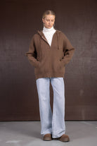 אישה עם סווטשרט חום עם רוכסן, גולף לבן, ג'ינס רחב ונעלי חורף חומות, אופנת חורף לנשים