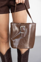 תיק יד חום לאישה עם אבזם מתכת, סטייל אופנתי, מגפיים חומים ומכנסיים קצרים