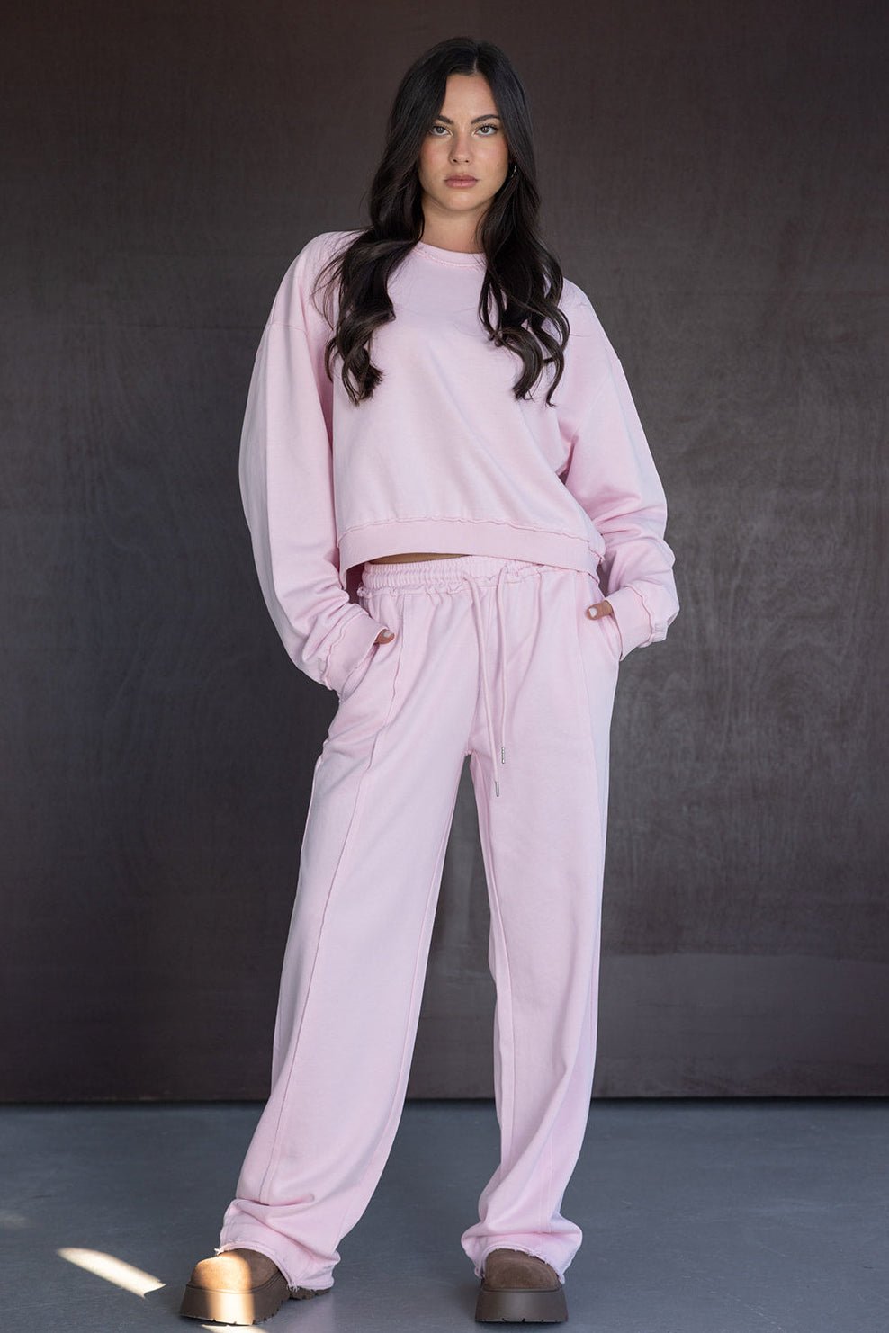 אישה לובשת סט טרנינג ורוד עם מכנסיים וחולצת סווטשרט רחבה, בגדי אופנה לנשים