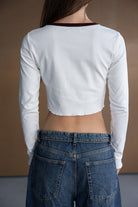 חולצת בייסיק לבנה ארוכה עם גזרה קצרה, מכנסי ג'ינס קלאסיים, תצוגת גב