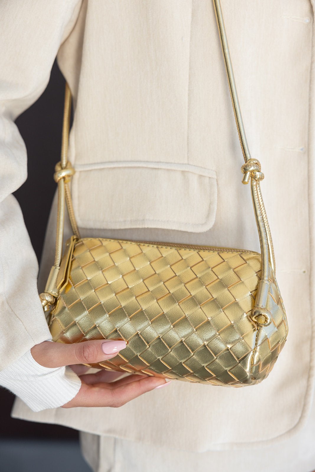 תיק צד קטן לנשים בצבע זהב מטאלי, עיצוב קלוע אופנתי, מוצג עם חליפה בהירה