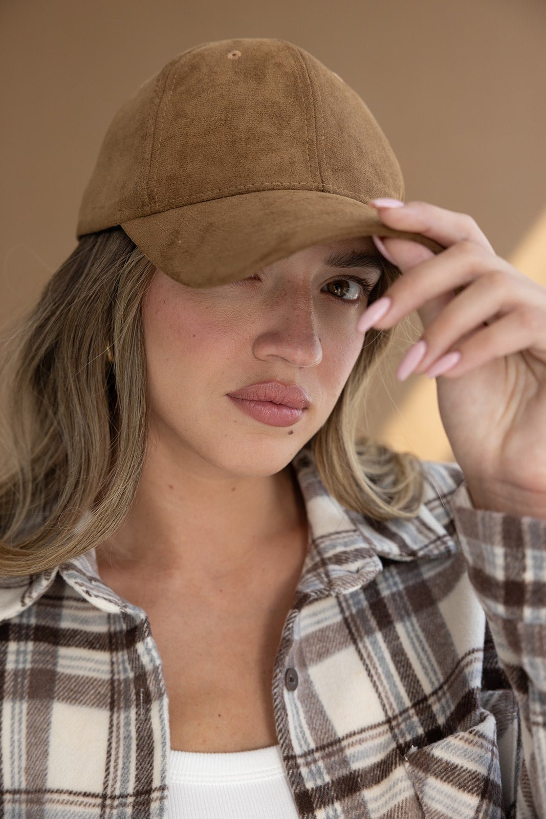 אישה עם כובע קאמל קטיפה, חולצת פלנל משובצת ואופנת נשים חורפית