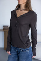 אשה לובשת חולצת נשים ארוכה בצבע כהה עם כפתורים וג'ינס, אופנת קז'ואל מעודכנת