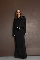 אישה לובשת שמלת מקסי שחורה עם שרוך לבן, משקפי שמש, אופנת נשים מודרנית