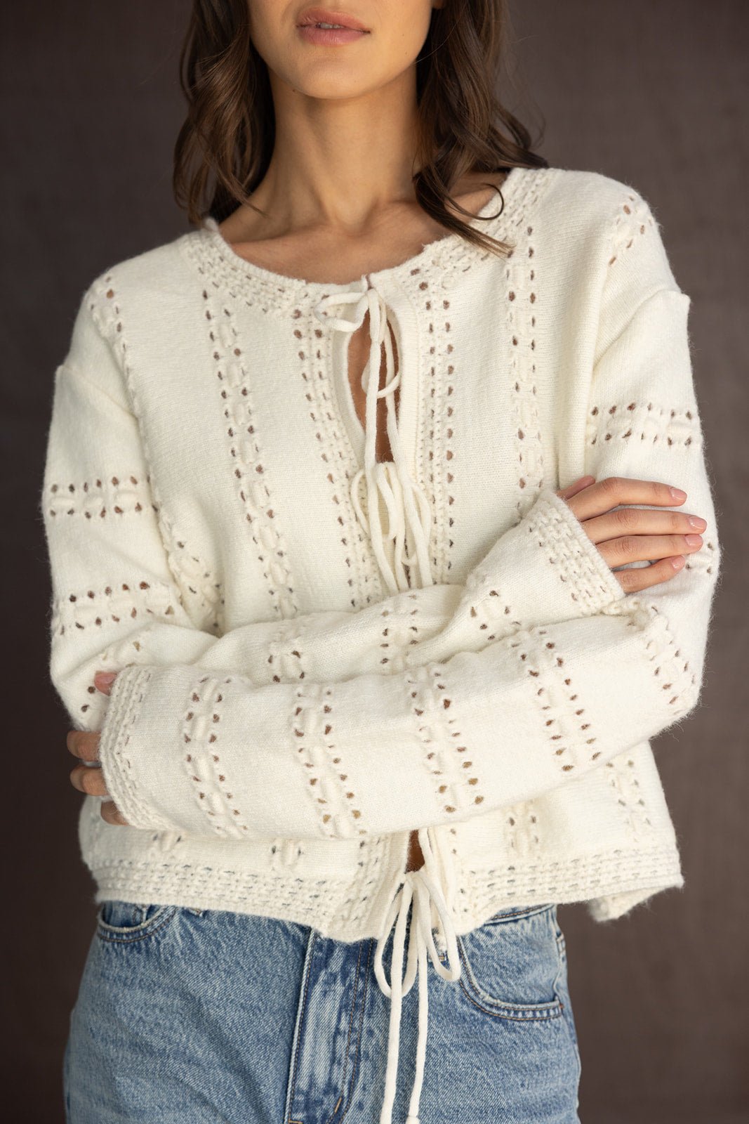 סוודר נשים סרוג לבן עם שרוך קדמי ודוגמת חורים, בשילוב ג'ינס קז'ואל אופנתי