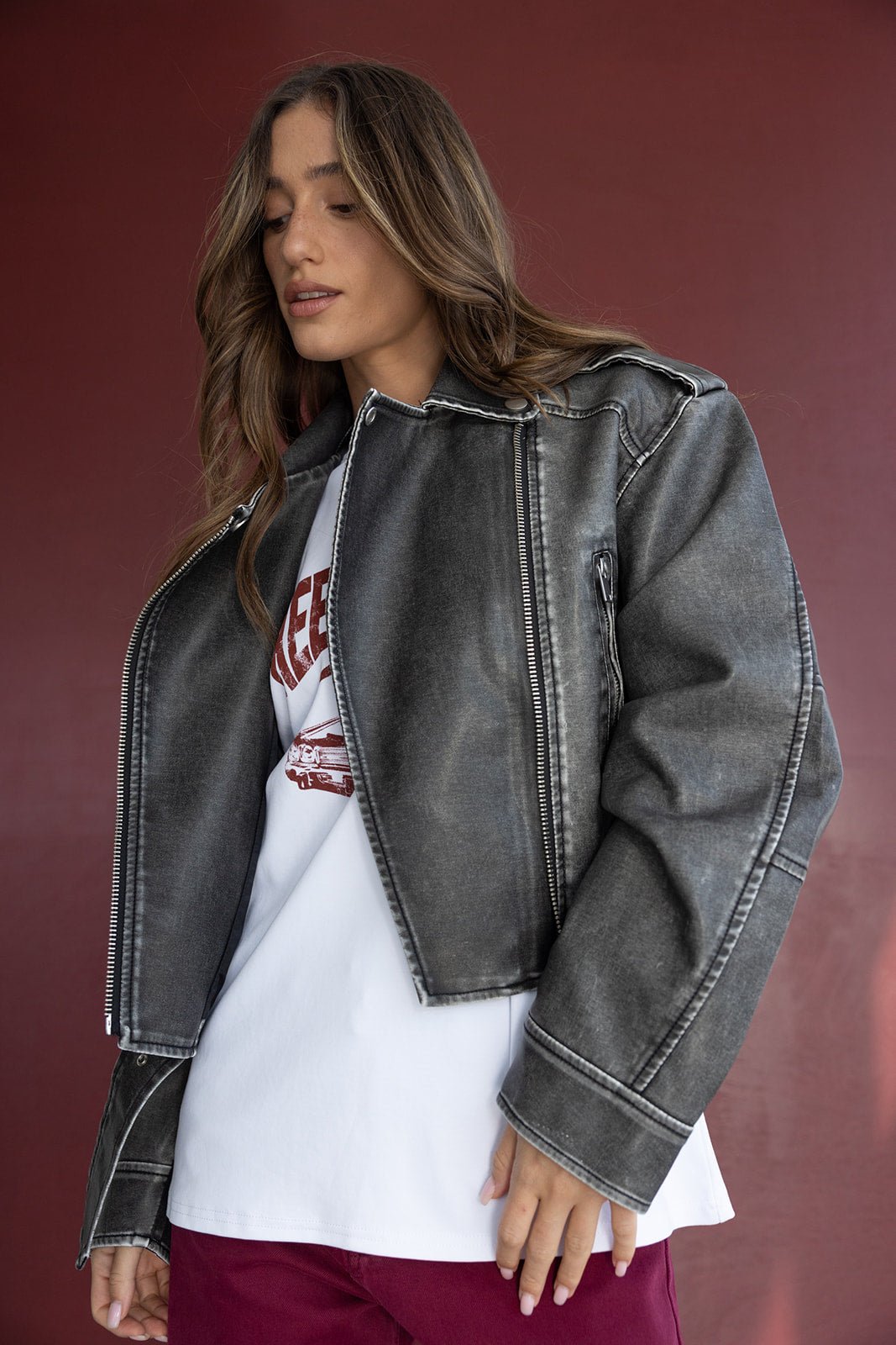 דוגמנית לובשת ג'קט ג'ינס אפור בסגנון אוברסייז עם חולצת טי לבנה ומכנסיים בורדו, אופנת נשים טרנדי