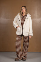 דוגמנית לובשת מעיל פלאפי שמנת וחליפת פסים חומה, אופנת חורף לנשים ונערות