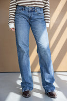 מכנסי ג'ינס נשים בגזרה ישרה, חולצת פסים חומה ונעליים חומות, אופנת קז'ואל צעירה