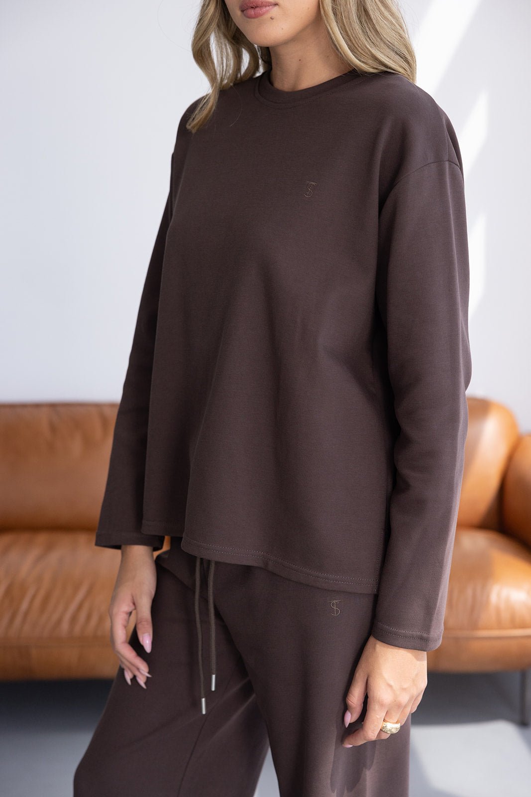 סט טרנינג נשים בצבע חום כהה, חולצה ארוכה ומכנסיים נוחים, צילום פנים ביתי אופנתי