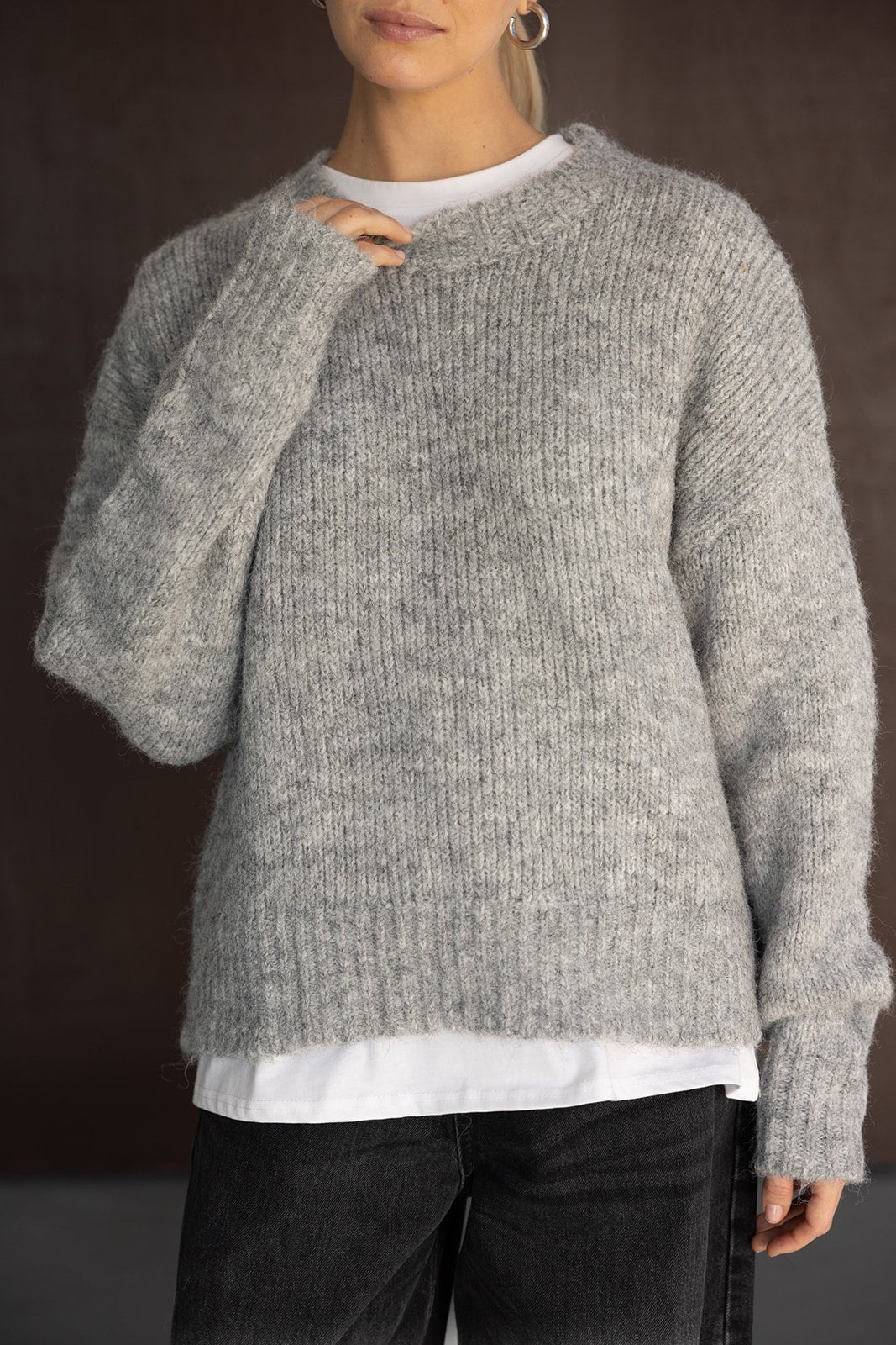 סוודר נשים אפור סרוג, מראה קז'ואל חורפי, עם טי שירט לבנה וג'ינס שחור