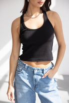 אישה עם גופיית ספורט שחורה וג'ינס גבוה אופנתי, לוק קז'ואל לנשים צעירות