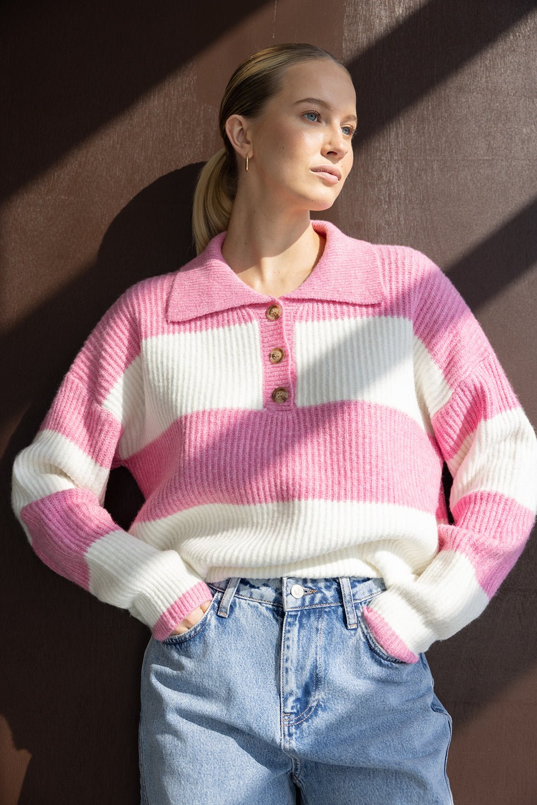 דוגמנית עם סוודר פסים ורוד ולבן ומכנסי ג׳ינס, אופנת נשים ונערות