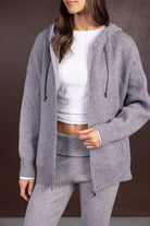 אישה לובשת סט טרנינג אפור סרוג, סווטשירט קפוצ'ון ורוכסן עם טופ קצר ובגד תואם, אופנת נשים חורפית