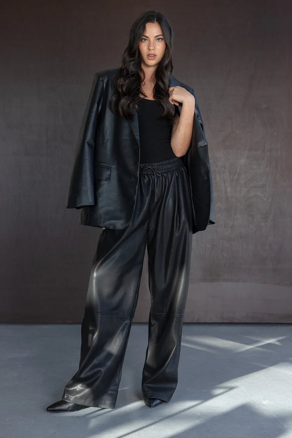 דוגמנית לבושה בז'קט ומכנסיים עור שחורים אופנתיים, חולצה שחורה, מראה אלגנטי לנשים.