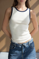 גופיית נשים לבנה עם שוליים כהים ומכנסי ג'ינס באופנת קיץ צעירה