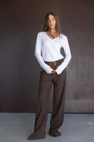 דוגמנית עם חולצת וי לבנה ארוכה ומכנסיים מחויטים רחבים בצבע חום, אופנה לנשים