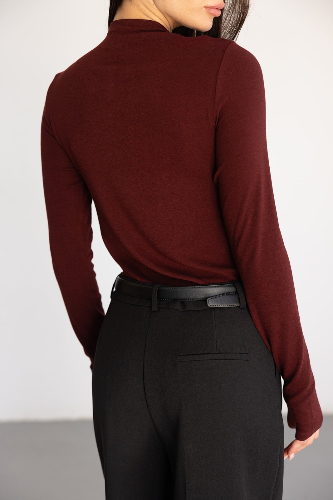 חולצה ארוכה בורדו לנשים עם שרוולים מלאים, משולבת עם מכנס מחויט שחור חגורה אופנתית