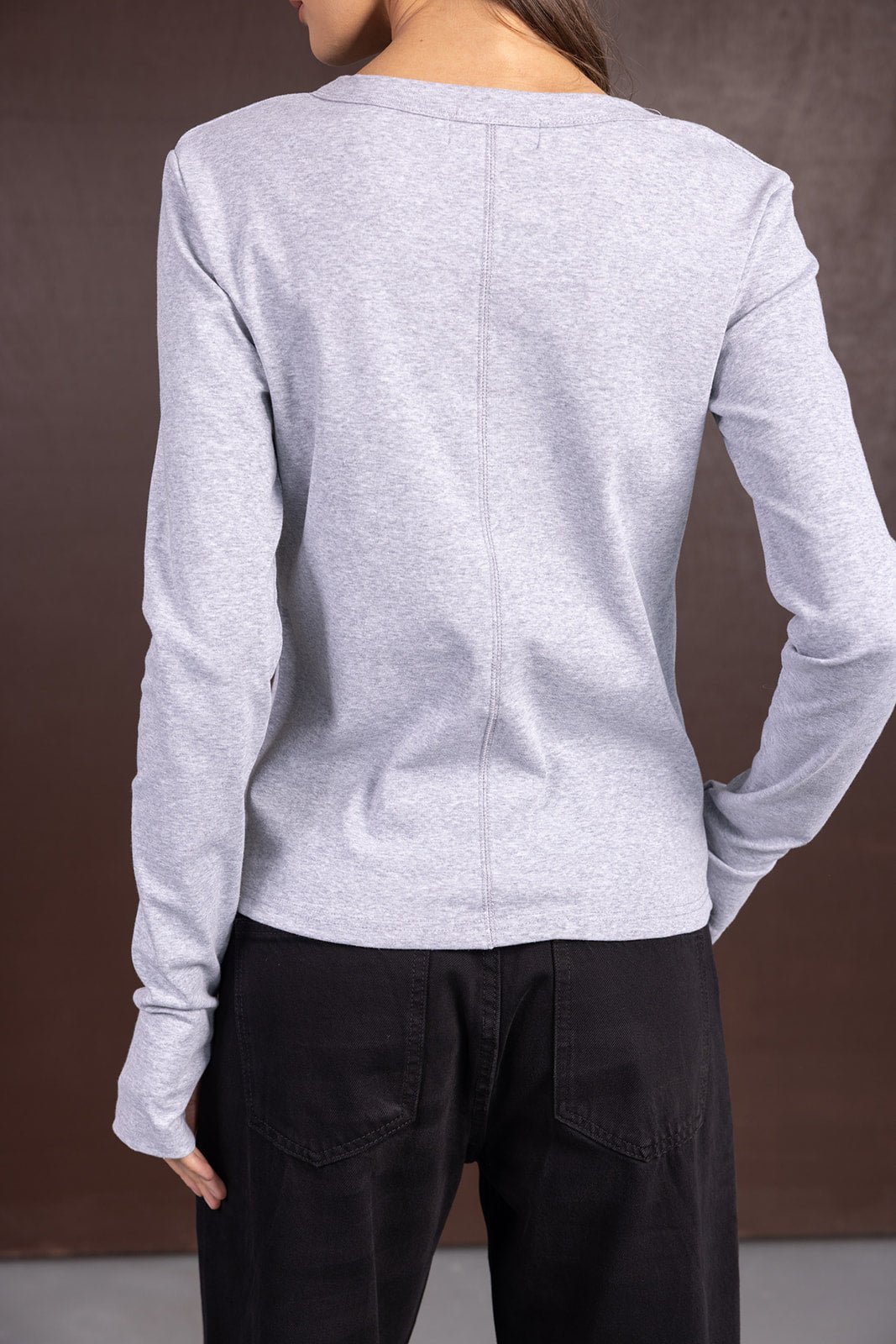 חולצת נשים ארוכה בצבע אפור, מכופתרת מאחור, עם מכנסי ג'ינס שחורים, צילום בגדי אופנה