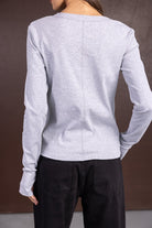 חולצת נשים ארוכה בצבע אפור, מכופתרת מאחור, עם מכנסי ג'ינס שחורים, צילום בגדי אופנה