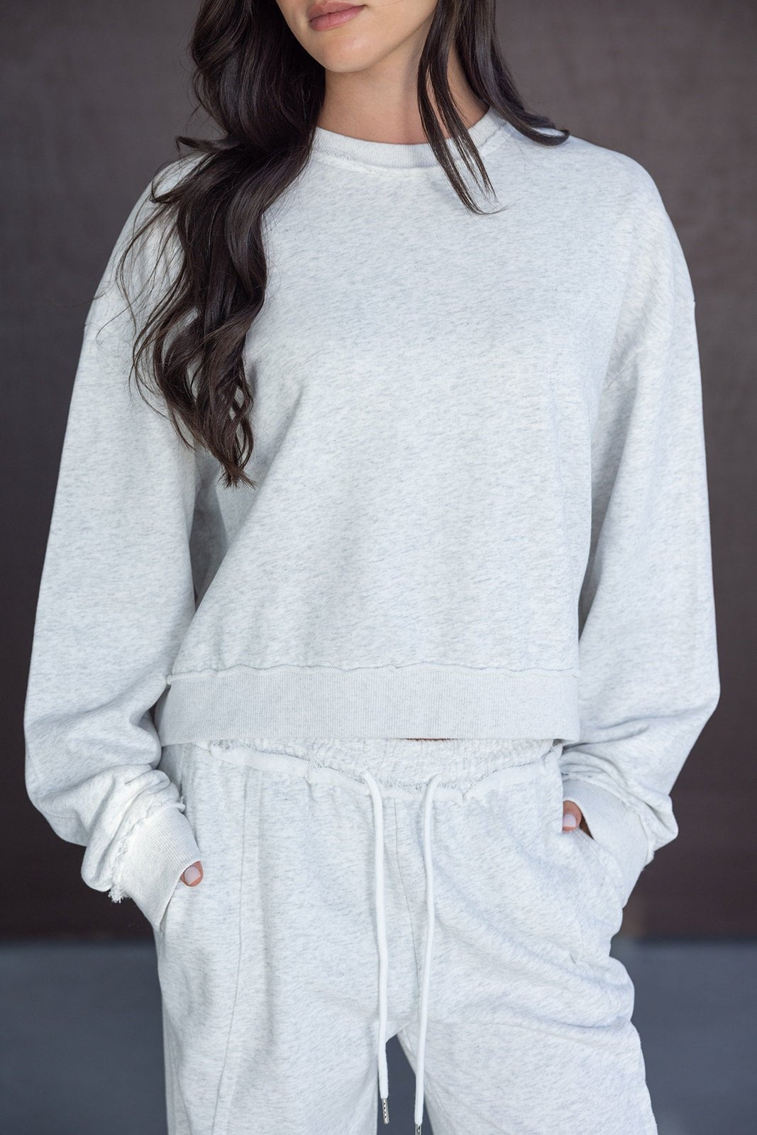 אישה לובשת סט טרנינג אפור לנשים, חולצת סווטשירט ומכנסיים קצרים בסגנון קז'ואל