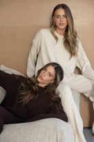 שתי נשים לובשות סטים סרוגים טרנדים, אחת בצבע בז' ואחת בצבע חום, אופנת חורף לנשים