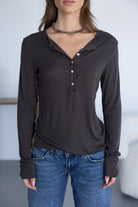 אישה לובשת חולצת טי שחורה עם שרוולים ארוכים וכפתורים, ג'ינס קז'ואל, לוק אופנתי לנשים