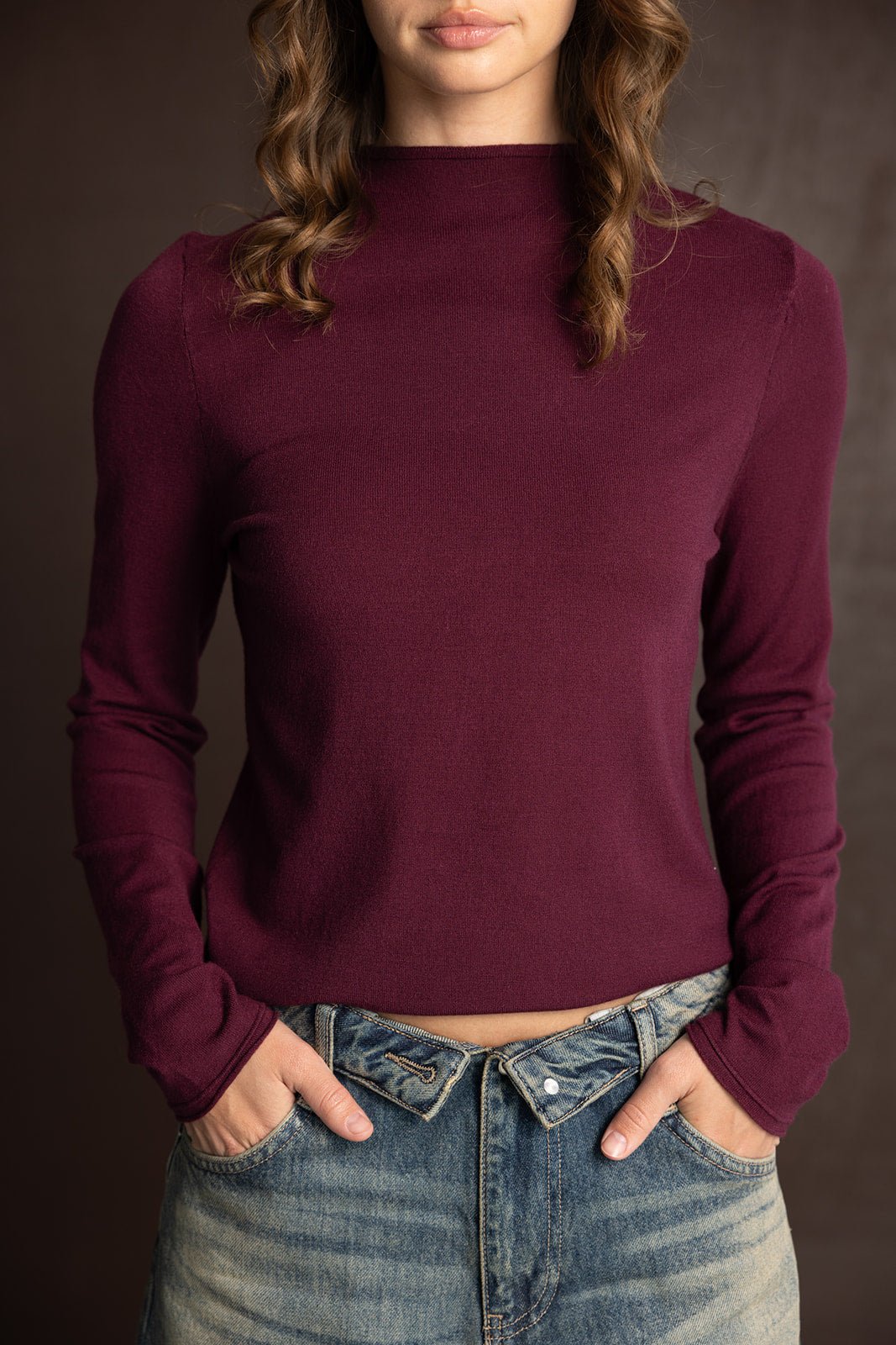 חולצת נשים בורדו עם שרוולים ארוכים וצווארון גבוה, משולבת עם ג׳ינס בגזרה גבוהה