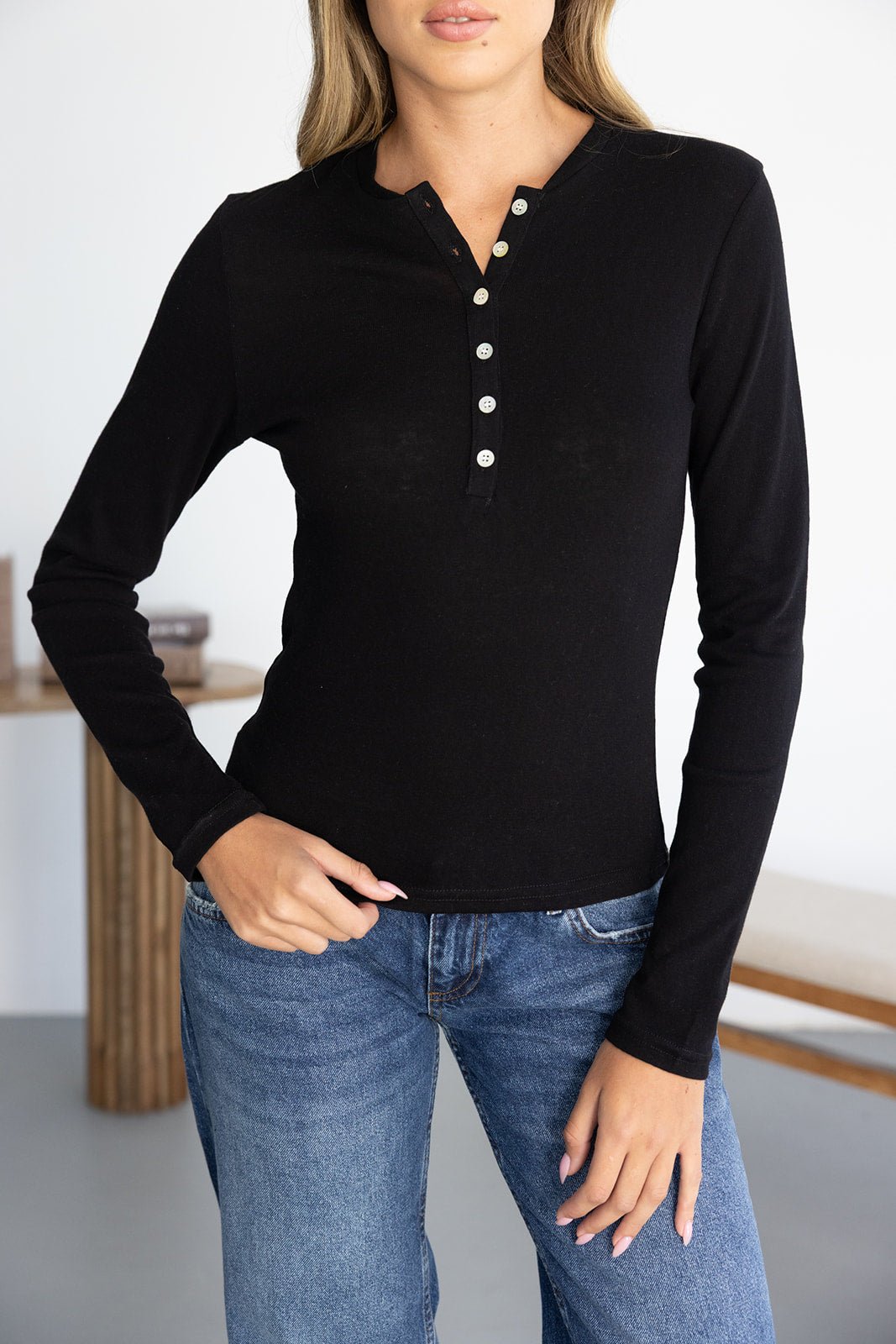 חולצת נשים שחורה עם שרוולים ארוכים וכפתורים, משולבת עם ג׳ינס לאופנת קז'ואל