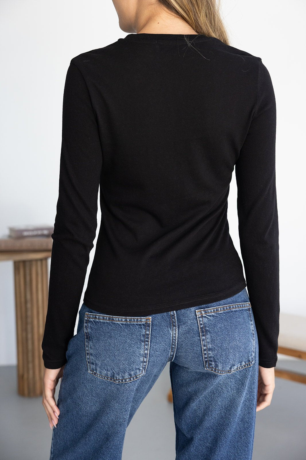חולצה שחורה ארוכה לנשים עם ג'ינס כחול קלאסי, מבט מהגב, אופנה צעירה ויומיומית