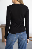 חולצה שחורה ארוכה לנשים עם ג'ינס כחול קלאסי, מבט מהגב, אופנה צעירה ויומיומית