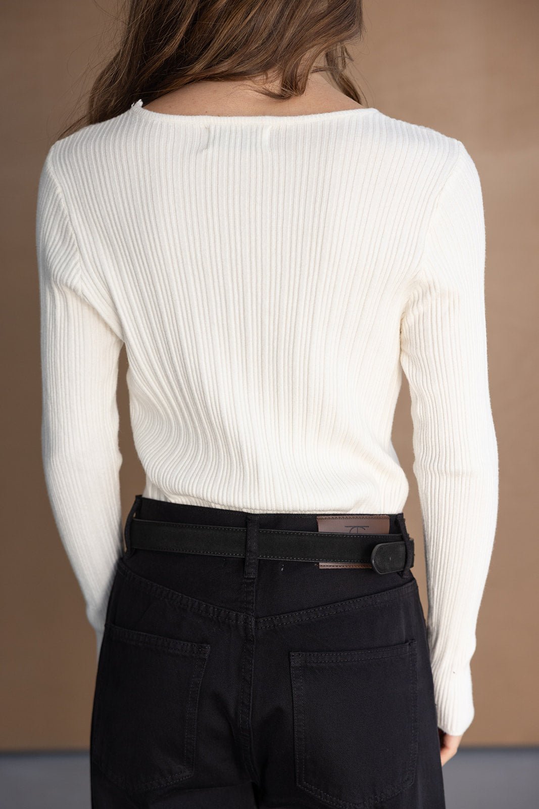 חולצת נשים סריג לבנה עם שרוול ארוך בשילוב ג'ינס שחור, מבט מאחור