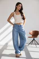 אישה עם גופיה לבנה ומכנסי ג'ינס רחבים, אופנת נשים צעירה בסגנון קז'ואל מודרני