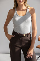 אישה עם גופיית סבא אפורה ומכנסיים חומים עם חגורת עור, אופנת נשים קז'ואל