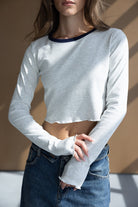 דוגמנית לובשת טופ קרופ שרוול ארוך בצבע אפור וג׳ינס גבוה, אופנת נשים לנערות