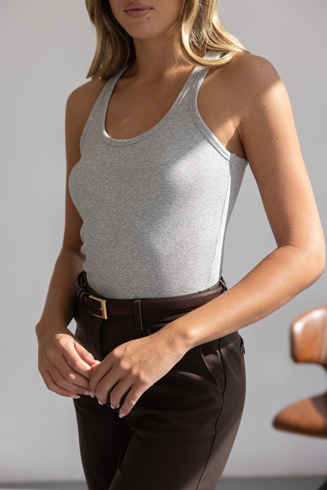 אישה לובשת גופיית ריב אפורה ומכנסיים חומים אופנתיים עם חגורה, סטייל קז'ואל לנשים