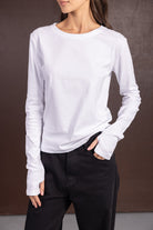 אישה לובשת חולצת כותנה לבנה ארוכה ומכנסיים שחורים, לוק קז'ואל אופנתי לנשים